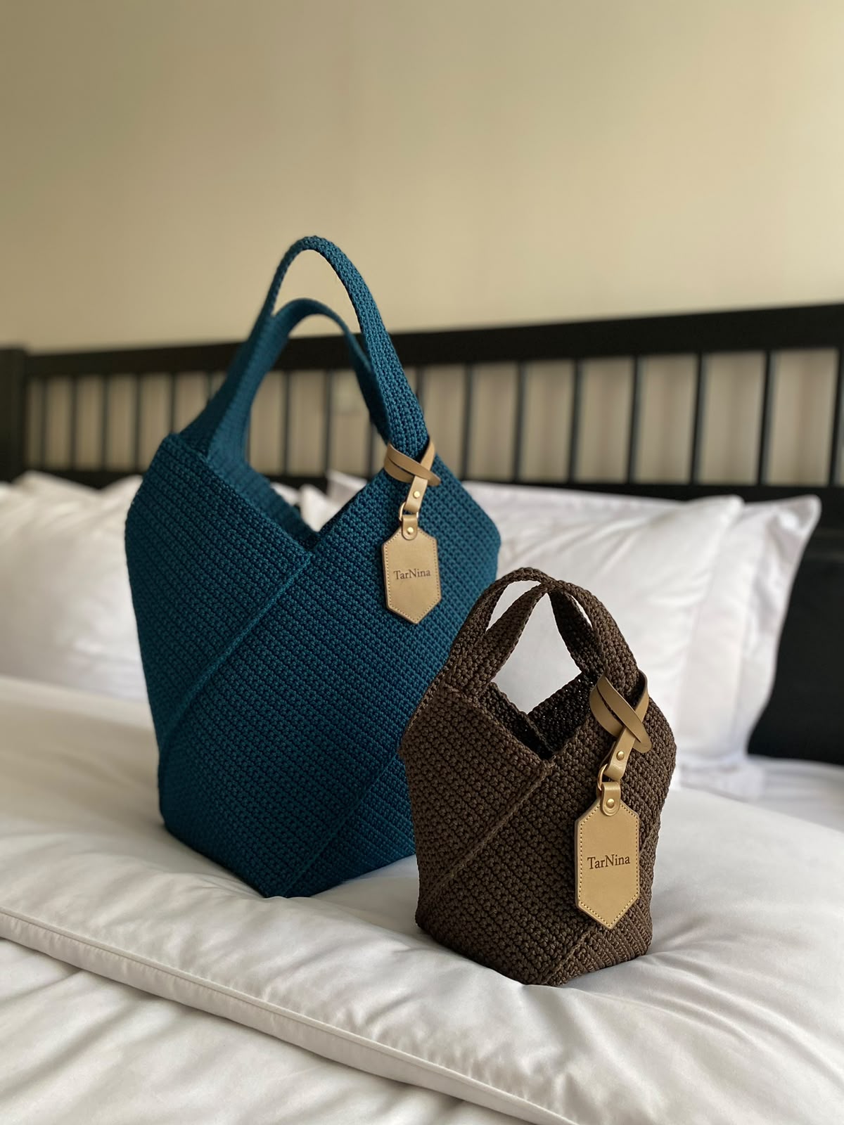 Two TarNina handcrafted bags — a teal tote and a small espresso-brown bag — displayed together with their signature leather tags